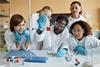 Students in a lab watching a teacher demonstrating a practical