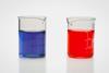 Two glass beakers containing red and blue liquids
