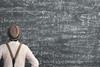Man standing in front of large blackboard covered in confusing equations