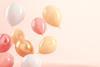 Celebratory, pale, shiny balloons floating against a pale flat background