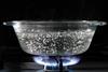 A glass dish of boiling water on a gas hob