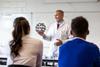 A chemistry teacher showing a high school class a model of buckminster fullerene