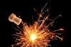 An image of a cork flying from an explosion effect created by a sparkler against a black background