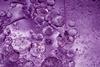 A close-up, full-frame image of bubbles of different sizes in a purple liquid