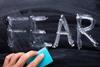 An image showing the word FEAR written in chalk and partially erased with a sponge