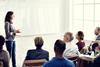 Teacher presenting to adults in front of a whiteboard
