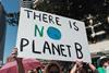 Photo of a woman holding a sign that reads 'there is no planet B'.