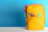 Yellow back pack with pencils and pencil case sticking out of the pockets
