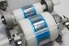 Two rollers with sticky tape on spread out a silvery substance in to a fine layer