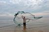 A fisherman in Baucau, East Timor, casts a net in the water to catch small fish