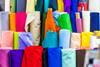 Bolts of colourful cloth on sale at local fabric market store.