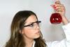 A chemistry student looking at a beaker of red liquid