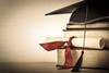 A mortarboard and diploma atop a pile of books