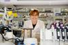 Dr Geertje Van Keulen is smiling in a laboratory filled with equipment and items, including petri dishes and pipettes.