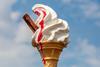 A photo of a melting ice cream cone with raspberry sauce and a flake