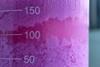 A macro photograph of a glass measuring cylinder containing purple cobalt carbonate formed by a precipitation reaction