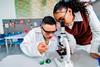 In a classroom, teacher helping a high school student with Down's syndrome to use a light microscope