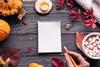 Using a notepad on a table with pumpkins, hot chocolate and autumnal leaves