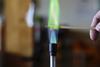 Copper solution burning on a wooden splint in a bunsen burner flame, producing a green flame