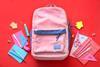 Photograph of top view school backpack and stationery on colour background