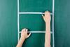 woman's hands on different rungs of a ladder drawn on a green chalkboard