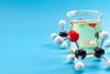 Molecular structure of chemical compounds and organic chemistry concept with educational plastic model of ethanol molecules and glass flask isolated on blue background with copy space