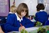 Primary school pupil writes in her book while looking at plants
