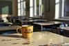 A colourful mug which says Good Morning with steaming coffee on a teacher's desk at the front of an empty classroom before the school day begins.