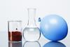 A brown powder in a glass beaker, a clear liquid in a carafe and a gas in a blue balloon.