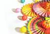 Brightly flamboyant fans with baubles round the edge and pumpkins on on top, laying on a table