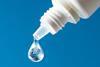 A dropper bottle with a drop of liquid that contains a globe