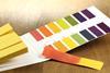 A photograph showing a booklet of detachable strips of universal indicator paper, with a colour chart for comparison