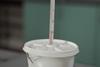 Thermometer stuck through hole in lid of polystyrene cup