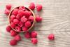 A bowl of raspberries on a wooden table
