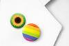 The lapel of a white lab coat with a sunflower badge and a rainbow badges