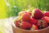 A bowl of strawberries with grass in the background
