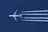 A passenger jet plane flying overhead leaving trails of vapour