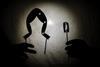 Some shadow puppets casting their silhouette on a sheet of a pair of frog's legs and a battery