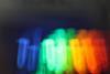 Blue, green, yellow, orange and red light visible from luminescent test tubes against a black background