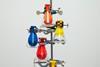 A number of glass conical flasks attached by clamps to a metal stand. Each flask has a colourful balloon sealed around its neck that has been sucked inside the flask.