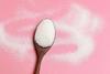 Sugar on a wooden spoon with a pink background