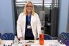Lynsey Findlay wearing a lab coat manning the science club table at a school fair