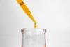 orange drop of liquid falling from pipette into flask