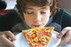picture of a boy smelling a slice of pizza