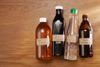 A photograph of four bottles containing different varieties of vinegar, including apple cider, black, white and malt vinegar