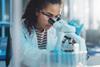 Female scientist looks through a microscope in the laboratory