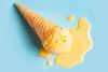 A vanilla ice cream in a waffle cone that has fallen on the floor and melted