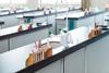 A school lab with no people but each station has equipment ready for a practical lesson including test tubes in a rack, with a holder and brush as well as a stirrer and pipette