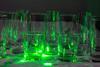 Green laser shone through tumbler glasses that reflect the light