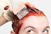 Red hair dye being applied to a woman's hair with a brush